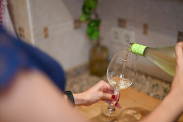 a girl pouring sparkling white wine into a wine glass

