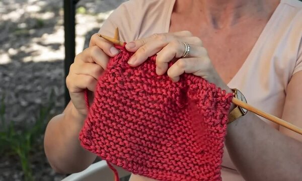 Femme tricotant de la laine rouge &eacute;paisse au point mousse pour un projet fait main