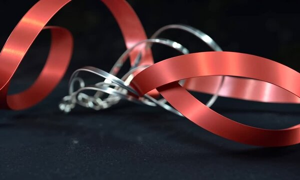 Bijoux entrem&ecirc;l&eacute;s avec un bolduc rouge sur fond sombre, cadeau romantique pour la Saint-Valentin