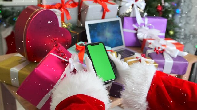 Santa hands holding phone green screen scrolling web sites and apps, festive background Christmas gifts boxes and fir tree. Close up.