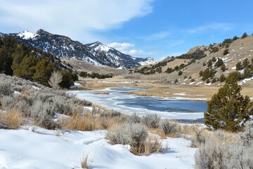 Winter landscape with snow-covered mountains and a glistening river under a blue sky