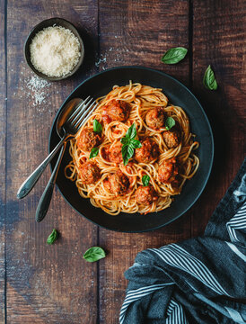 Top view of plate of spaghetti and meatballs on wooden table.