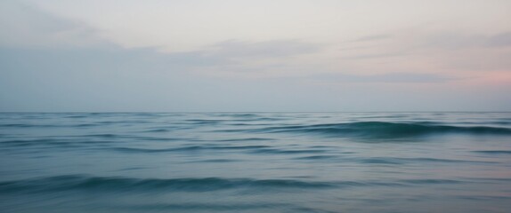 Calm blue ocean water under overcast sky in twilight.