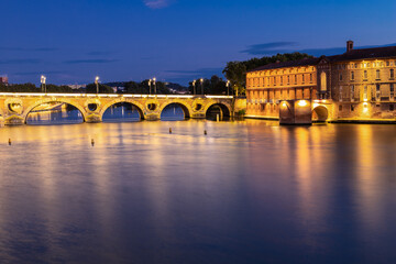 Golden sunset over the Garonne river and Pont Neuf in downtown Toulouse. This arch bridge is considered a masterpiece of the Renaissance. The bridge is not symmetrical.