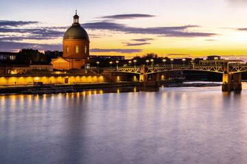 Fototapeta premium Golden sunset over Garonne river with views on the the pedestrian Saint-Pierre bridge, Place Saint-Pierre and the Grave hospital seen from the riverside 