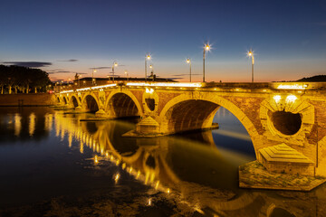 Fototapeta premium Golden sunset over the Garonne river and Pont Neuf in downtown Toulouse. This arch bridge is considered a masterpiece of the Renaissance. The bridge is not symmetrical.