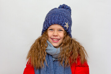 Portrait of caucasian happy smiling little girl in red down jacket with blue hat and scarf of 6 7 years old