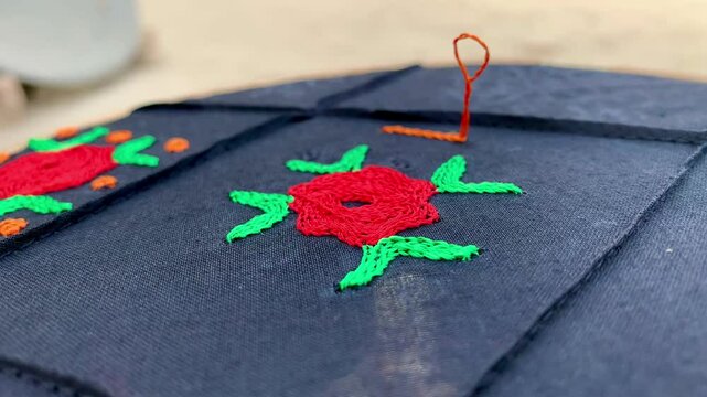 A black color fabric with hand embroidered flower in red and green colors