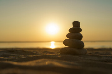Zen stones background. Pyramid of stones on the background of sunset on the sea beach. Relax, balance, calm, concept.