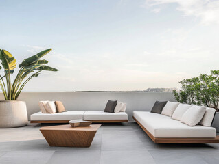 Modern outdoor lounge with stylish seating and greenery overlooking a coastal view at sunset