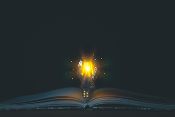A glowing light bulb emerges from an open book, symbolizing knowledge, and new ideas. Concepts of...