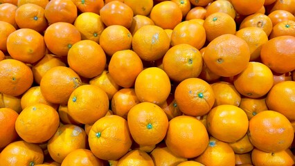 A vibrant pile of fresh oranges, bursting with color and invitingly juicy, waits for customers to hand-pick the perfect fruit, offering a refreshing and nutritious choice for any time of day.