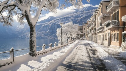 Fototapeta premium Winter view of Riva del Garda town, its streets dusted with snow, overlooking the calm waters of Garda Lake with snow-covered mountains in the background.