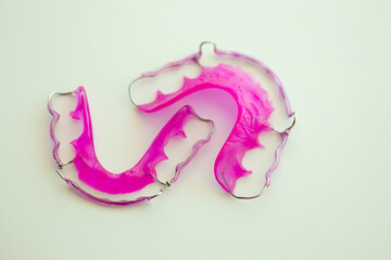 Pink acrylic dental retainer on white background