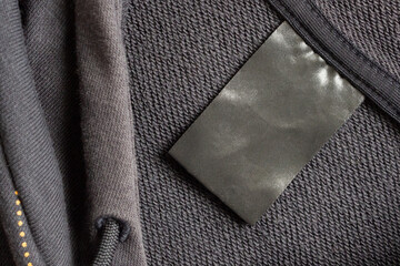 Blank black laundry care clothes label on black fabric texture background