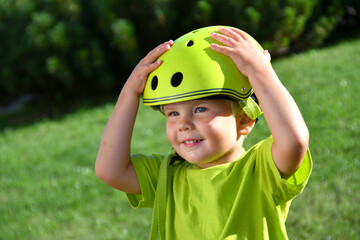 little boy putting on a safety helmet before riding a scooter or bike