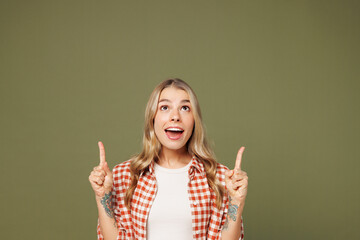 Young happy woman wear red shirt white t-shirt casual clothes point index finger overhead indicate on empty workspace area isolated on plain pastel green background studio portrait. Lifestyle concept.