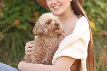 Smiling woman with cute dog in autumn park, closeup