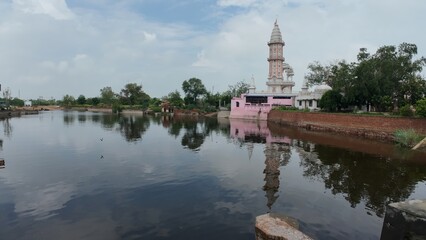 Tranquil pond in a village, showcasing a temple complex, embodying calmness and serving as a sacred pilgrimage destination. Haryana, India 