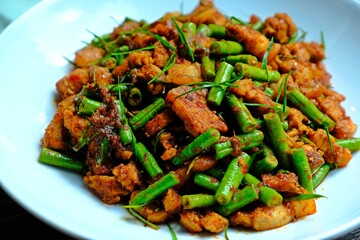 Stir fried crispy pork belly and yard long bean with ginger red curry paste, Authentic Thai food.