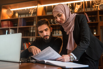 Business team of young man and Muslim woman working together on the project planning strategy in...