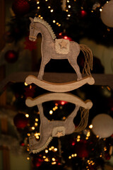 Children's toy wooden horse
 Against the background of a Christmas tree with coffee with lights on
