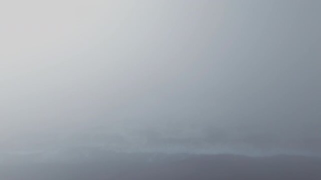 Camera rising above cinematic white thick fog above beautiful ocean clouds at sunrise. Cinematic drone aerial above endless sea of clouds until the horizon. Amazing nature landscape with blue sky 4K