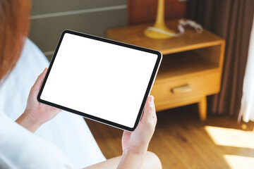 Mockup image of a woman holding digital tablet with blank desktop screen at home