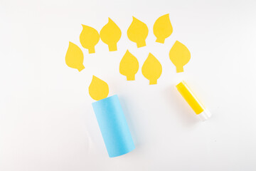 yellow flame shape piece attached to blue color tube, step in creative process, DIY, how to make paper candle garland yourself using simple paper cutouts