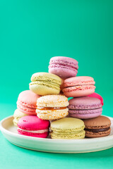 Macarons in the form of a Christmas tree in a plate on a green background. Vertical orientation.