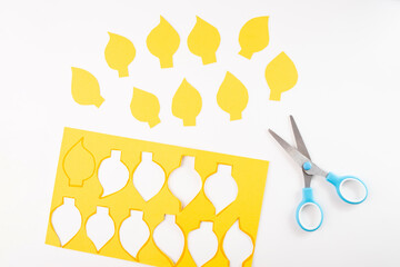 yellow paper cutouts in the shape of flames, crafting activity, step in creative process related to art projects or educational purposes,