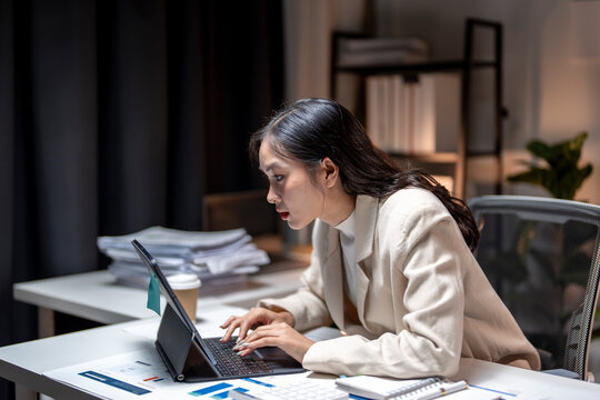 Young asian businesswoman working late using laptop computer in office at night
