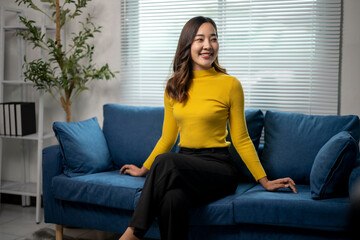 Obraz premium Young businesswoman smiling while sitting on sofa in modern office