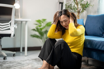 Young businesswoman feeling stressed and having a headache while sitting on the floor in her home...