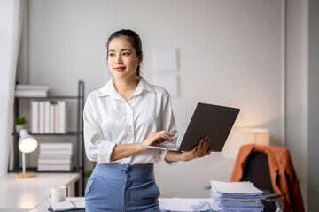 Businesswoman working on laptop and thinking about project in modern office