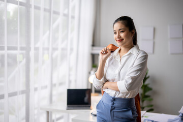 Obraz premium Young asian businesswoman smiling and looking through office window