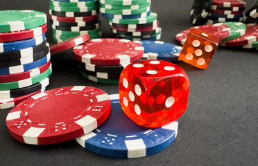 Red dices on casino table with poker chips on background