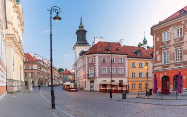 Dawn view of a colorful street in the Old Town of Warsaw, Poland, with historical buildings, cobblestone sidewalk and outdoor seating areas