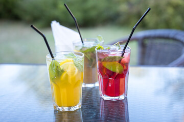 Three drinks with straws in them are on a table