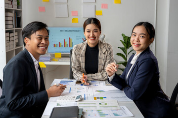 Three women and a man are sitting at a table with a lot of papers and graphs