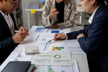 Three people are sitting at a table with papers and pens
