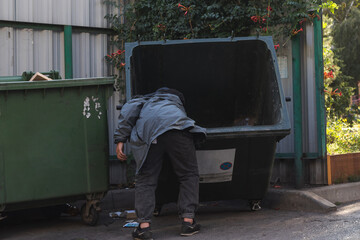 A homeless man digs through garbage in search of food.