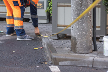 A municipal worker in uniform renews the road lines