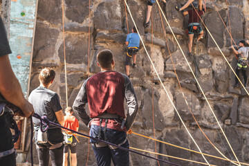 Sport men at the rock climbing wall outside  looking at her friend on the track