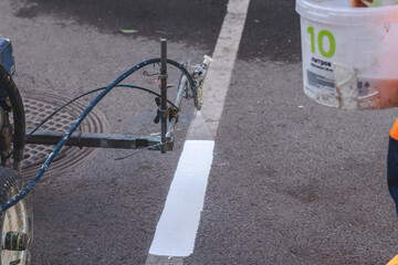 A municipal worker in uniform renews the road lines.  In a jar special composition 10 liters