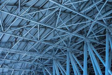 Roof of production facility, view from inside. Hangar ceiling with lighting fixtures. Factory building made of metal structures. Industrial architectural structure. Exhibition center ceiling