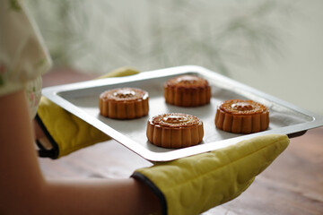 Close-up of woman holding pan with baked sweet cakes