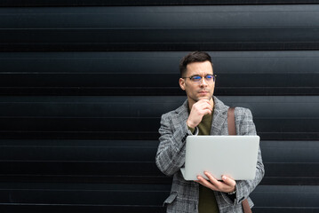 Portrait of young businessman standing outside office building. Successful professional office...