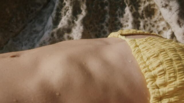 Belly and torso of a woman lying breathing and relaxing on a beach after swimming, Marseille, France