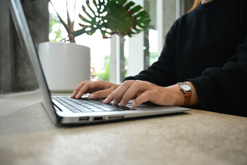 Close up shot of young female freelancer hands typing on laptop keyboard